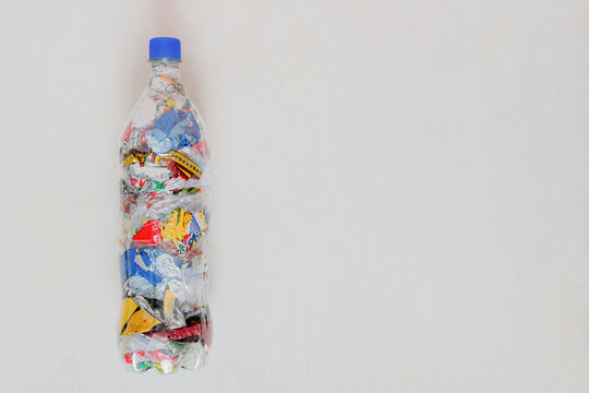 eco brick PET bottle stuffed with plastic waste on white background	
