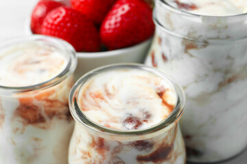 Tasty yoghurt with jam and strawberries on table, closeup