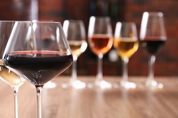 Tasty red and white wines in glasses against blurred background, space for text