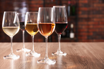 Different tasty wines in glasses on wooden table, space for text
