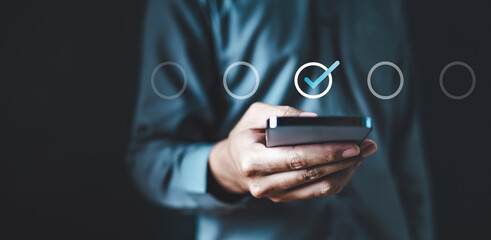 check, mark, correct, answer, wireless, future, global, management, press, information. A man is holding a cell phone with a blue check mark on it. Concept of accomplishment or satisfaction.