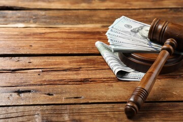 Judge's gavel and money on wooden table, closeup. Space for text