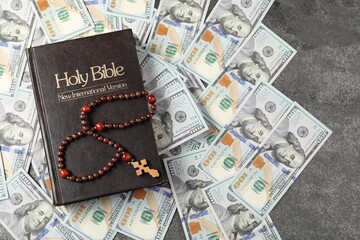 Holy Bible, cross and money on grey table, top view