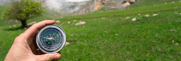 Travel compass in traveler's hand, mountain view