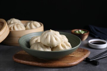 Delicious bao buns (baozi) in bowl on grey table, closeup