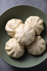 Delicious bao buns (baozi) in bowl on grey table, top view