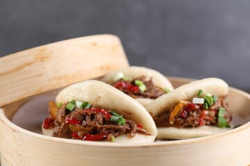 Delicious gua bao (pork belly buns) in bamboo steamer on grey background, closeup