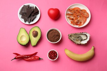 Natural aphrodisiac. Different food products and red decorative heart on pink background, flat lay