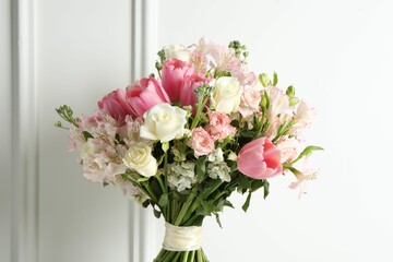 Beautiful bouquet of fresh flowers near white wall