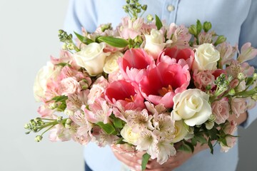 Woman with beautiful bouquet of fresh flowers on light background, closeup