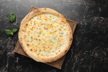 Delicious cheese pizza and basil on black marble table, flat lay