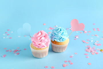 Delicious cupcakes with blue and pink frosting on color background. Gender reveal party concept