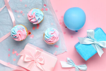 Delicious cupcakes with gift boxes and decorations on pink background. Gender reveal party concept