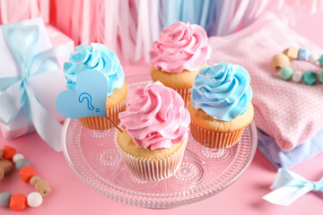 Delicious cupcakes with question mark, kid clothes and decorations on pink background. Gender reveal party concept