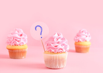 Delicious cupcakes with question mark on pink background. Gender reveal party concept