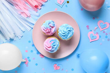 Plate with delicious cupcakes and decorations on blue background. Gender reveal party concept