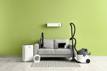 Couch with modern household appliances near light green wall in room