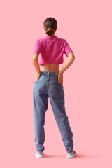 Naklejka premium Young woman in stylish jeans pants on pink background, back view