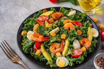 Seafood salad with shrimps, kale cabbage, avocado, tomatoes, croutons and quail eggsin a plate with...