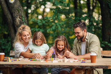 Young family is competing in building wooden towers in nature.