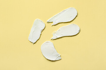Samples of cosmetic cream on yellow background