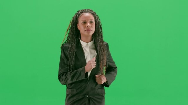 Young female reporter isolated on chroma key green screen background. African american woman tv news host running.