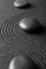 Fototapeta na wymiar Spa stones on black sand with lines, closeup. Zen concept