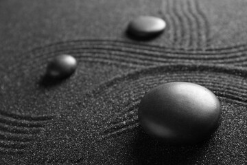 Spa stones on black sand with lines, closeup. Zen concept