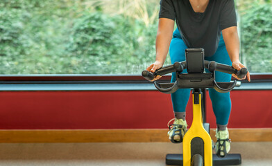 female exercising on a bike in a gym, banner with copy space