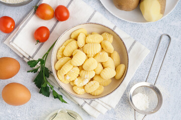 Bowl with tasty gnocchi, tomatoes and parsley on light background