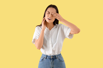 Young woman suffering from toothache on yellow background