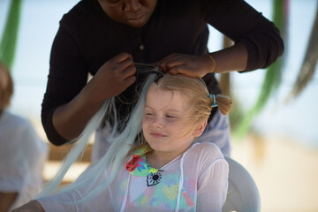 holding braids with pink color on little kid head. stylist applying braiding hair on young baby. - obrazy, fototapety, plakaty