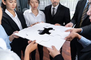 Multiethnic business people holding jigsaw pieces and merge them together as effective solution...