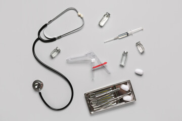 Stethoscope with gynecological speculum, syringe and ampules on white background