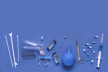 Gynecological speculum with pap smear test tools, pills and ampules on blue background