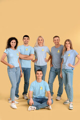 Obraz premium People with yellow awareness ribbons on color background. World Cancer Day