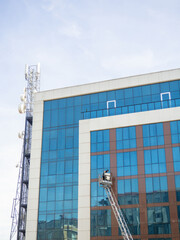Cleaning windows in a large glass building. Work at height on a lift. Man in a cradle.