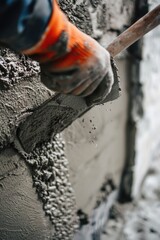 Close up of a person using a hammer to apply cement on a wall. Suitable for construction and renovation projects