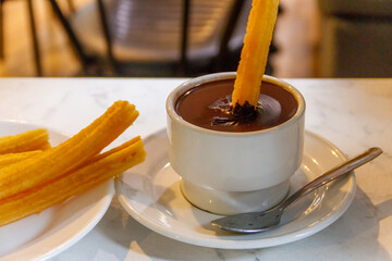 Dipping churros into hot chocolate mug. Churros - traditional spanish dessert