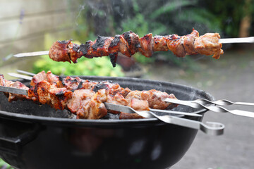 Cooking delicious kebab on metal skewers outdoors
