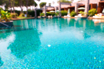 Luxury resort with outdoor swimming pool and sun loungers on sunny day, blurred view
