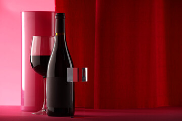 Stylish presentation of delicious red wine in bottle and glass on color background. Space for text