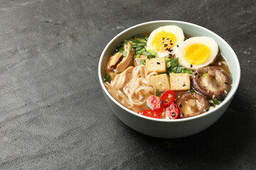 Noodle soup. Bowl of delicious ramen on black table, closeup. Space for text