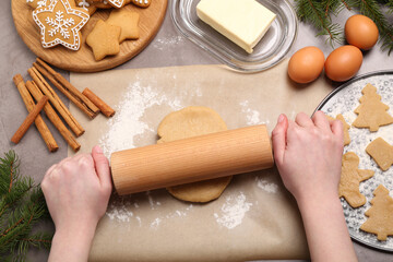 Making Christmas cookies. Woman rolling raw dough at grey table, top view