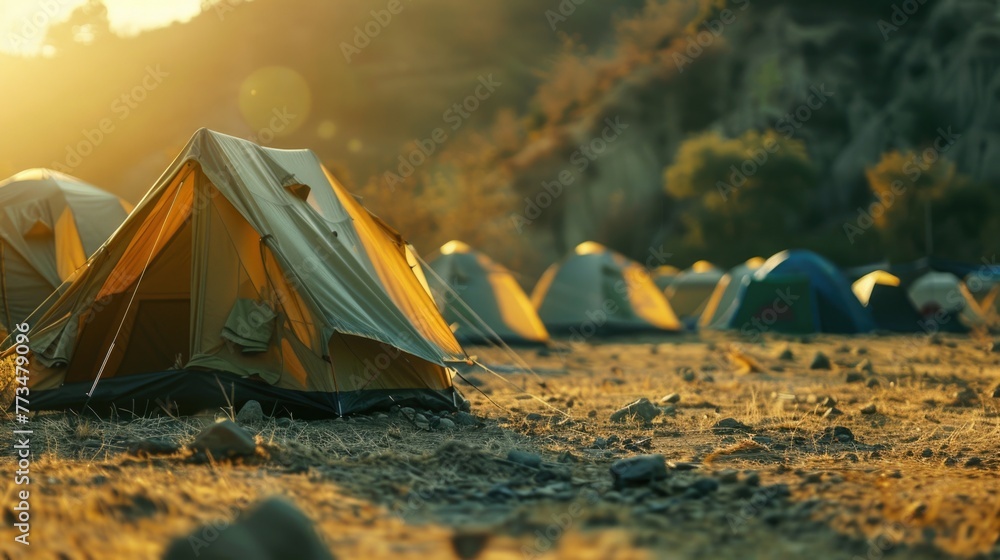 Poster a group of tents set up on a dry grass covered field. ideal for outdoor camping or event concepts