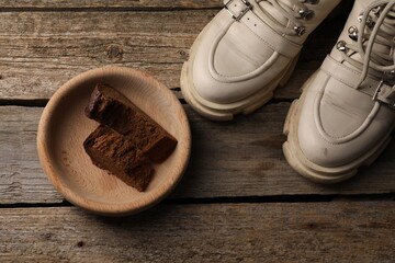 Poverty. Old boots and pieces of bread on wooden table, top view