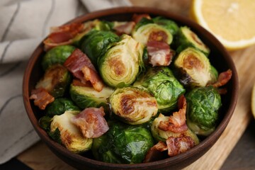 Delicious roasted Brussels sprouts and bacon in bowl on table, closeup