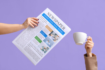Female hands with newspaper and cup of coffee on lilac background