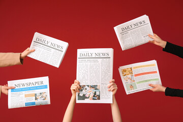 Female hands with newspapers on red background