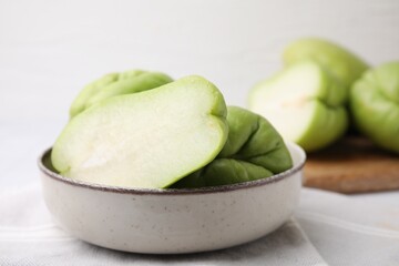 Cut and whole chayote in bowl on table, closeup